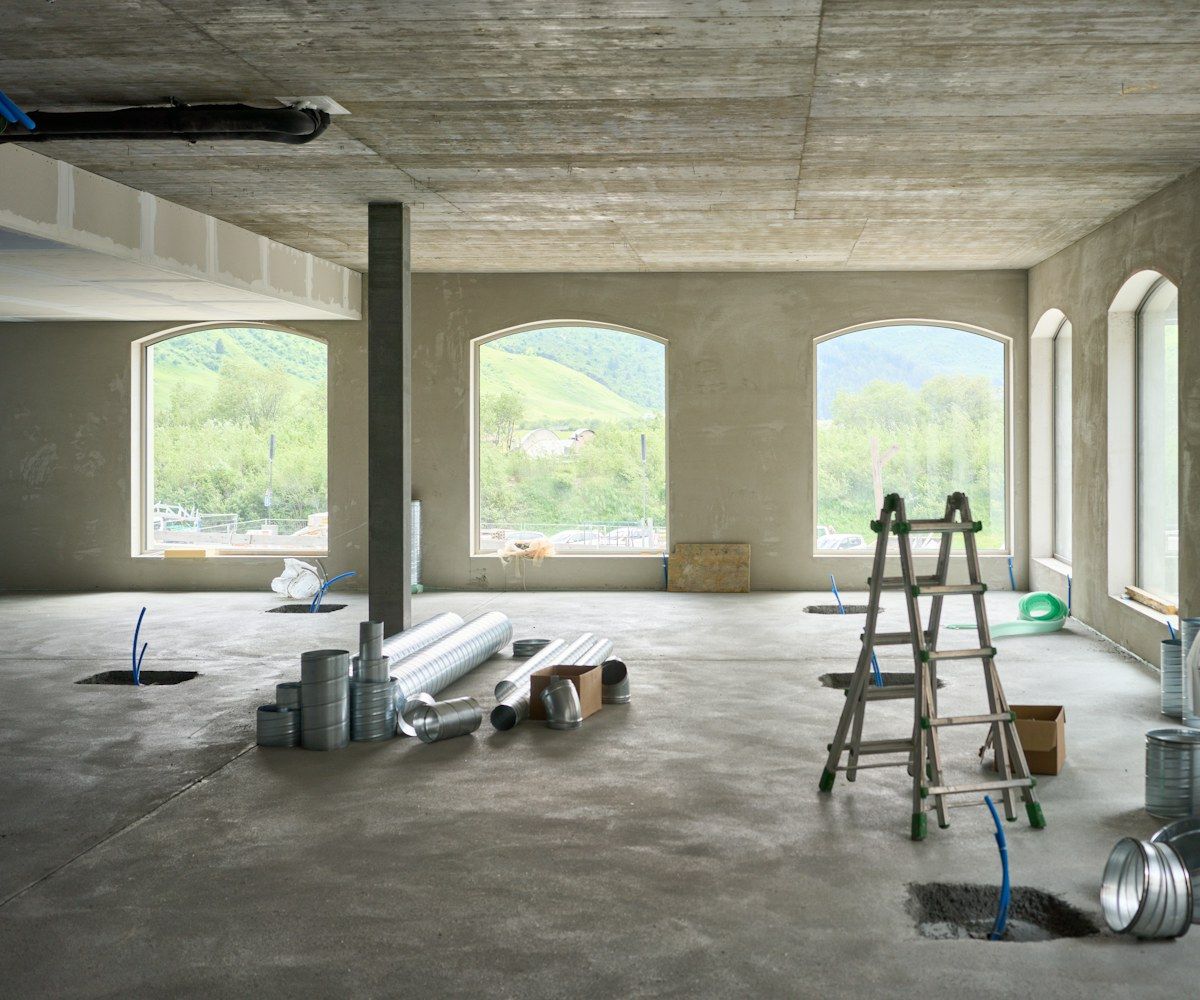 Rohbau-Innenraum mit Fenstern und Leiter vor der Bauendreinigung